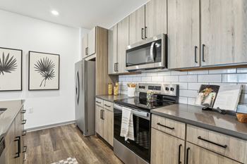 A modern kitchen with wooden cabinets and stainless steel appliances at The Junction at Rockledge Apartments, Rockledge
